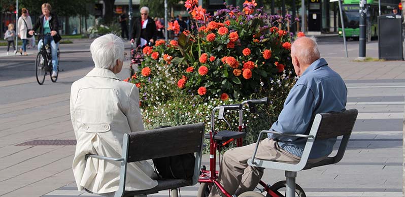 Äldre par som sitter och tittar på blommor och njuter av solen